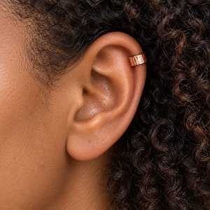 Hammered copper ear cuff shown being worn on the upper helix of a dark haired woman's ear