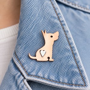 Copper terrier dog pin brooch with a silver heart, attached to a pale blue denim jacket lapel