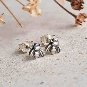Tiny fine silver bee stud earrings shown from the front with sterling silver posts