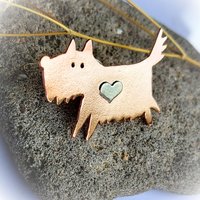 Angled view of the handcrafted copper scruffy terrier dog brooch with a sterling silver heart