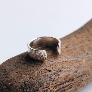Sterling silver hammered ear cuff photographed from the side to show its curved open design