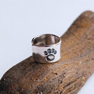 Close-up of a handcrafted sterling silver paw print helix cuff showing the hand-stamped paw print detail