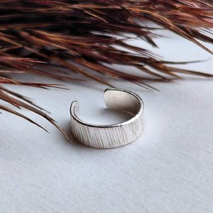 Close-up of hammered sterling silver ear cuff showing the organic texture and polished edges