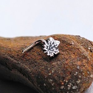 Fine silver maple leaf nose stud with a sterling silver L-shaped post, shown on natural wood