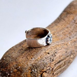Side view of the handcrafted sterling silver helix cuff showing the fine silver daisy flower and open design