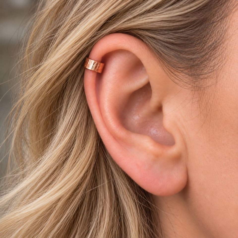 Hammered copper ear cuff shown being worn on the upper helix of a fair-haired woman's ear