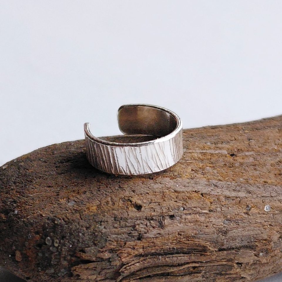Sterling silver hammered ear cuff with organic textured finish displayed on rustic wood