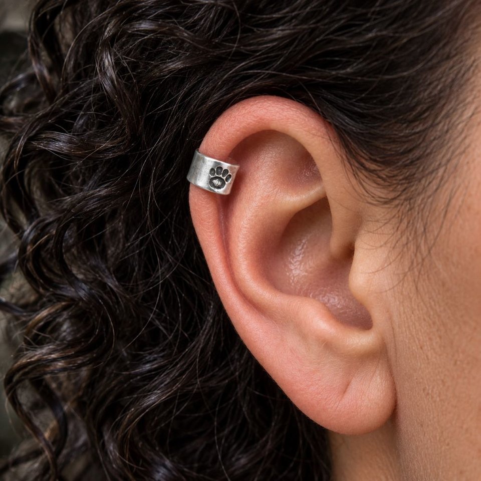 Sterling silver paw print helix cuff worn on the upper ear to show how it looks when fitted to the helix